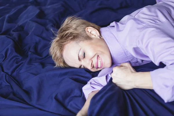 Frohen Morgen. schöne Frau liegt auf blauem Laken — Stockfoto