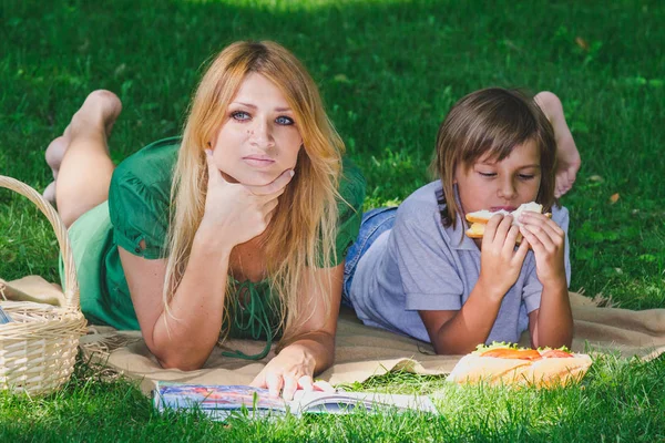 Rodinné snídani v trávě. Máma a syn jíst sendvič — Stock fotografie