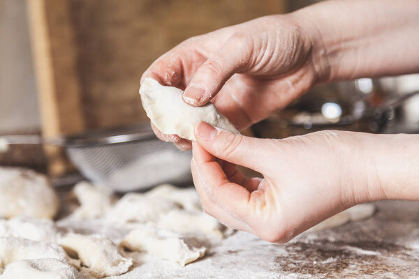 hands of woman make dumpling over granite table