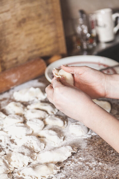 hands of woman make dumpling over granite table