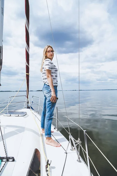 Slender barefoot blonde is standing on white yacht — Stock Photo, Image