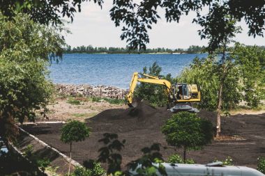 Sarı Ekskavatör nehir banka topraklarında digs