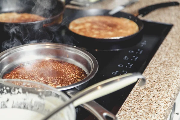cooking pancakes in several pans