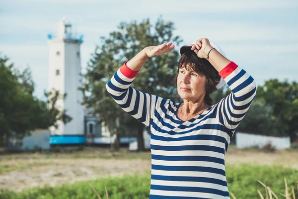 Oudere vrouw op zoek naar de afstand aan kust — Stockfoto