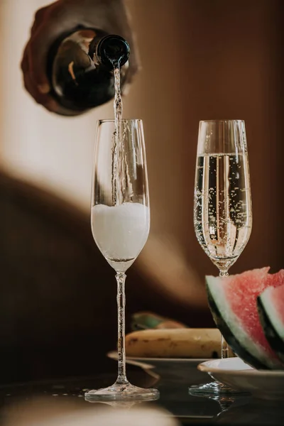 Рука наливает шампанское в высокие бокалы — стоковое фото