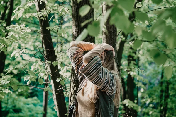 Slender blonde is standing in park in front of tree — Stock Photo, Image