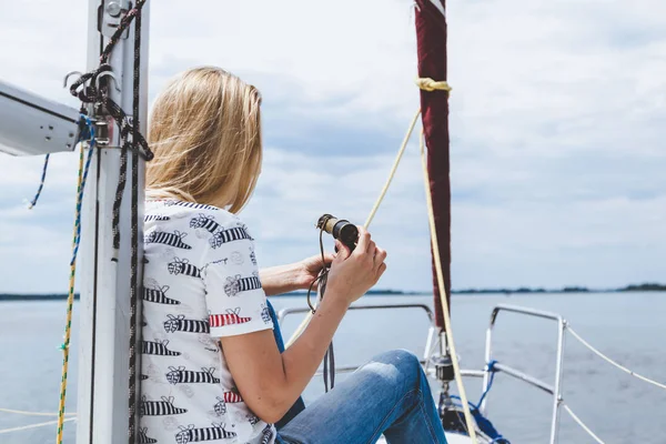 Slender blonde in jeans sits on nose of white yacht — Stock Photo, Image