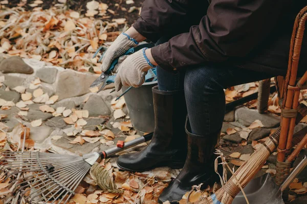 Woman in rubber boots sits among fallen leaves in yard — Stock Photo, Image