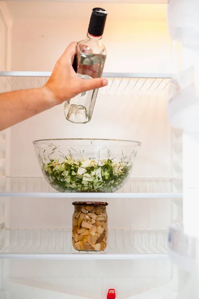 Hand takes  bottle of vodka in  white refrigerator — Stock Photo, Image