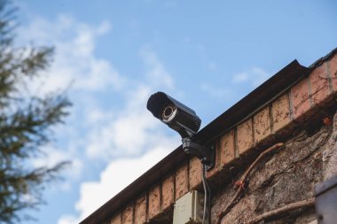 Mavi gökyüzünün arka planındaki güvenlik kamerası.