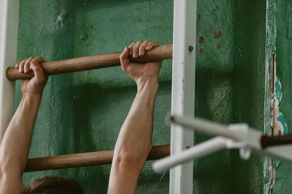 Руки спортсмена держатся за штангу гимнастической стены — стоковое фото