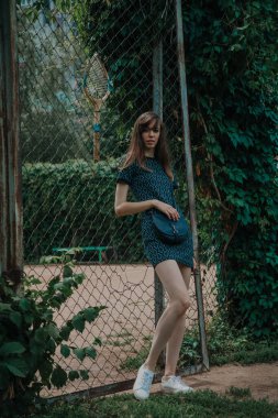 Genç ince kız tenis kortu önünde duruyor