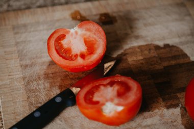 Kesilmiş kırmızı domates ahşap tahta üzerinde yatıyor