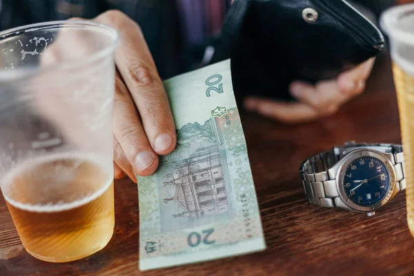 Hand is holding money near  glass of beer. Beer fee — Stock Photo, Image