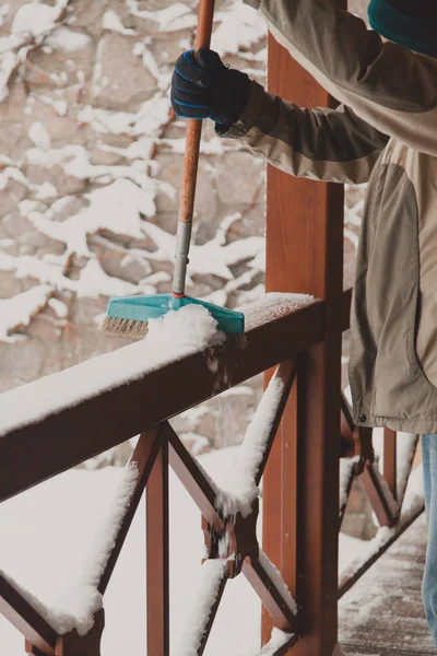 Travailleur nettoie la neige sur le porche avec une longue brosse — Photo