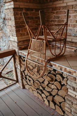 Boş verandada hasır sandalye ters duruyor.