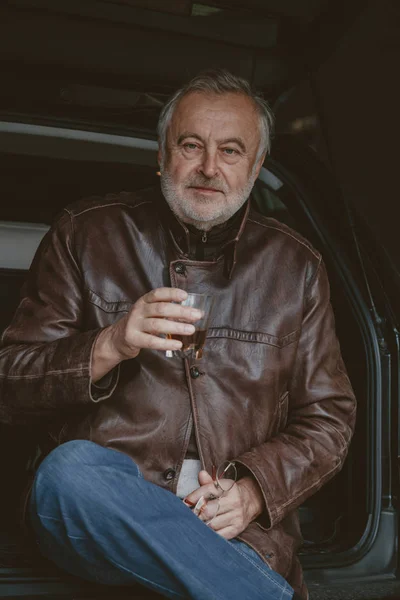Retrato de hombre de pelo gris con vaso de whisky en el coche — Foto de Stock