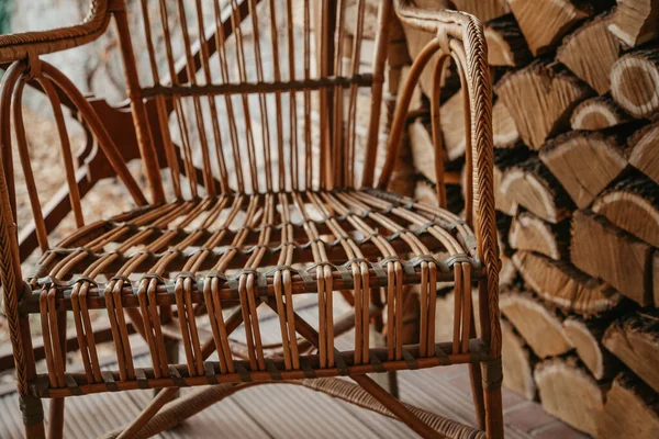 Cadeira de vime fica ao lado de madeira picada — Fotografia de Stock