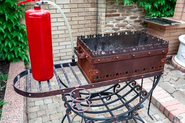 Vörös tűzoltó készülék áll a fém grill — Stock Fotó