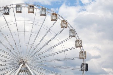 Çekiciliğe bakıyorum. Dönme dolapta beyaz bulutlu mavi gökyüzüne karşı kulübeler.