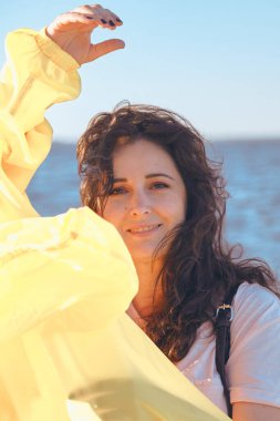 Uzun kızıl saçlı hoş bir kız su yüzeyinin arka planında duruyor. Doğal kusurlarıyla rötuş yapmayan bir kadının portresi