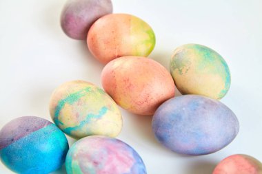 Paskalya tatiline özen göster. Farklı renklerde boyanmış birkaç tavuk yumurtası beyaz bir sırt grubunda.