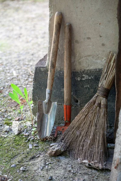 木柄上的小耙和勺子 以及建筑物角落里的扫帚 — 图库照片
