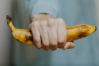 El adam beyaz bir sırt grubuna olgun bir muz sıkar.