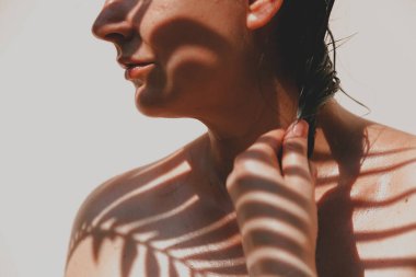 İnce yapraklı bir palmiye dalının gölgesi sırılsıklam olmuş omuzlarına ve güzel bir kızın yüzüne düşer. Doğal kusurlarıyla rötuşsuz portre.