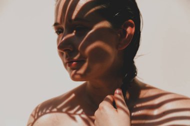 İnce yapraklı bir palmiye dalının gölgesi sırılsıklam olmuş omuzlarına ve güzel bir kızın yüzüne düşer. Doğal kusurlarıyla rötuşsuz portre.