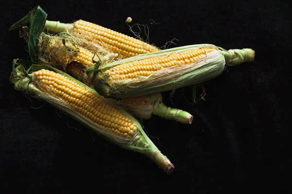 Appetitliche Maiskolben Mit Grünen Blättern Liegen Auf Schwarzem Hintergrund Großaufnahme — Stockfoto