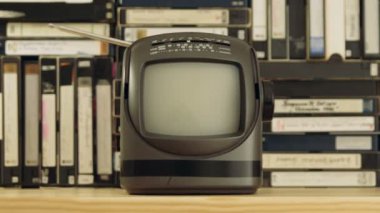 Vhs ve S-Vhs video kasetlerinden yapılmış arka plan antenli eski küçük TV seti. Kamera televizyondan uzaklaşıyor ve odak dışı. Dolly vurdu.