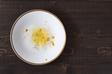 Yemekten sonra yemek artığı. Tek bir beyaz tabakta baharatlı sarı yağ. Ahşap masa arka planı. Fotokopi alanı olan üstten üste düz fotoğraf