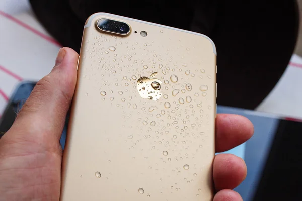 IPhone 7 Plus wodoodporny w ręku człowieka pokryte kroplami — Zdjęcie stockowe