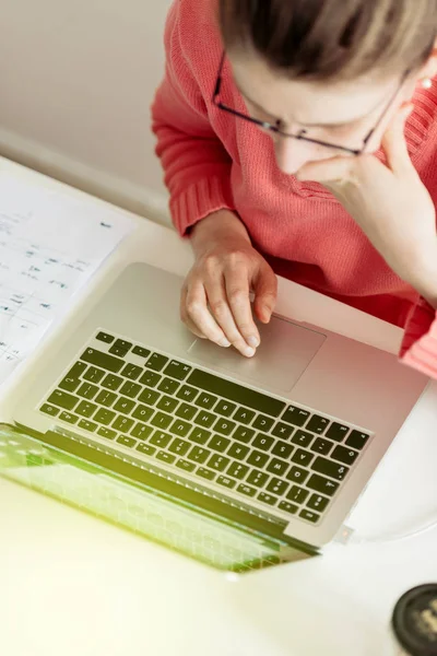 Thinkful 的妇女穿着粉红色的毛衣工作的笔记本电脑 视图从上面 — 图库照片