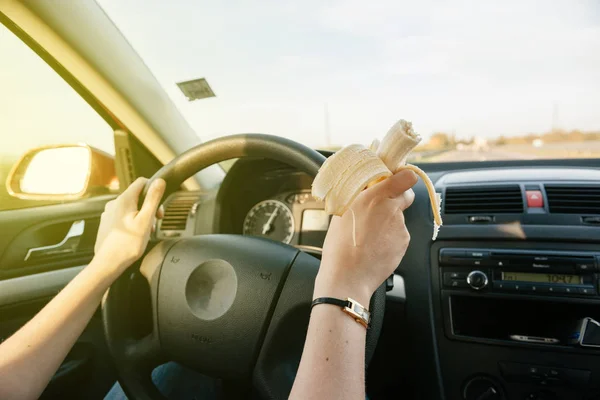 Mujer comiendo plátano mientras conduce — Foto de Stock