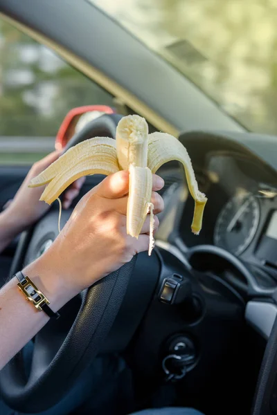 Woman eating banana while driving