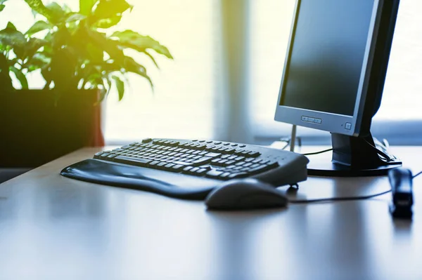 Сучасний комп'ютер на столі в офісі, освітлений сонцем — стокове фото