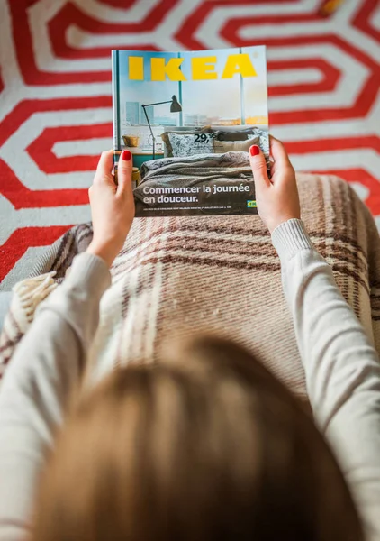 Mujer leyendo la cubierta del catálogo IKEA antes de amueblar la casa —  Fotos de Stock