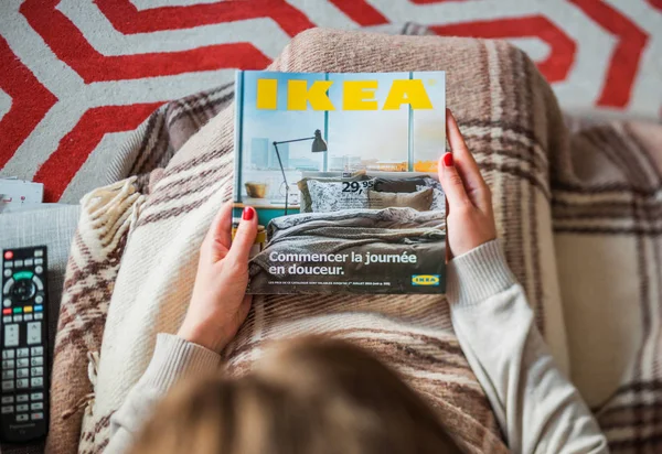 Mujer leyendo la cubierta del catálogo IKEA antes de amueblar la casa —  Fotos de Stock