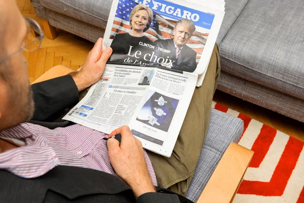 Человек, читающий французский журнал о Хиллари Клинтон и Дональде Трю — стоковое фото