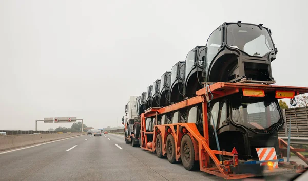 Rear view of a big truck with flatbed trailer hauling tractor ca — Stock Photo, Image