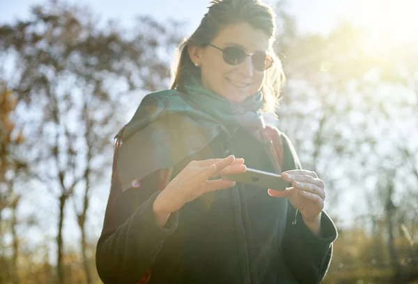 Woman using futuristic phone outdoor sun flare