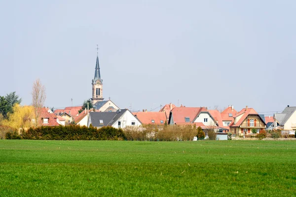 Деревня с церковью и зеленым сельскохозяйственным полем — стоковое фото