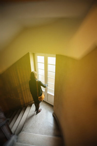 Женщина спускается по лестнице в старом здании
 