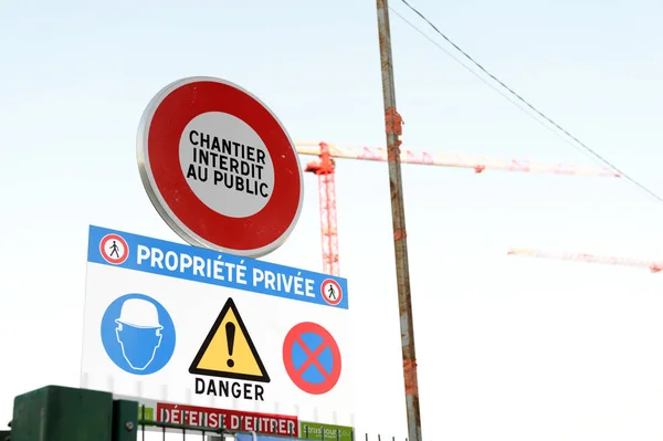 Construcción con grúas y señal de advertencia en la calle —  Fotos de Stock