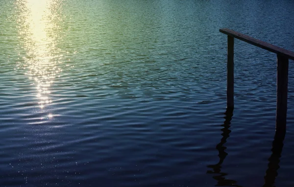 Beautiful pier with sparkling light on water surface — Stock Photo, Image