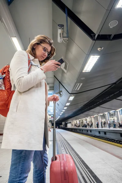 Κομψή γυναίκα χρησιμοποιώντας στο μετρό σιδηροδρομικό σταθμό σιδηροδρομικές σωλήνα smartpho — Φωτογραφία Αρχείου