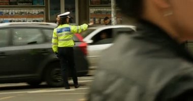 BÜKREŞ, ROMANIA - CIRCA 2017: Güçlü meslek - kadın polis memuru trafik denetimi Romanya 'nın başkentinde yoğun bir kavşağı izliyor
