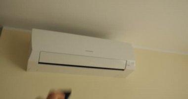 Adamın biri uzaktan kumandadan modern klimayı açıyor. Kışın otel havasını, yazın da soğuk havayı seçiyor.